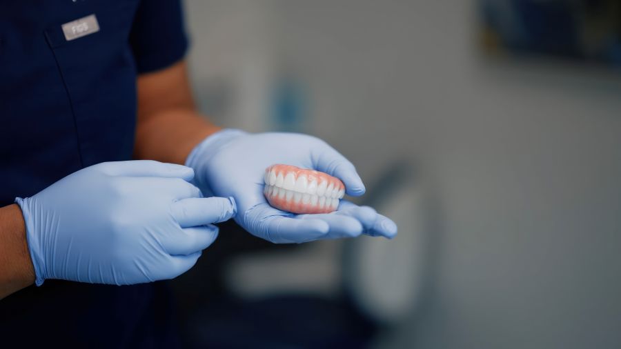 Gloved hand holding a set of zirconia teeth