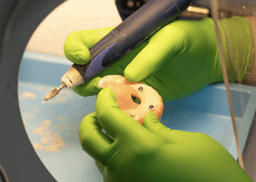 A dremel drill being used to shape the dentures and make holes for the dental implants.