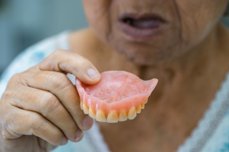 Woman holding top dentures in front of her mouth