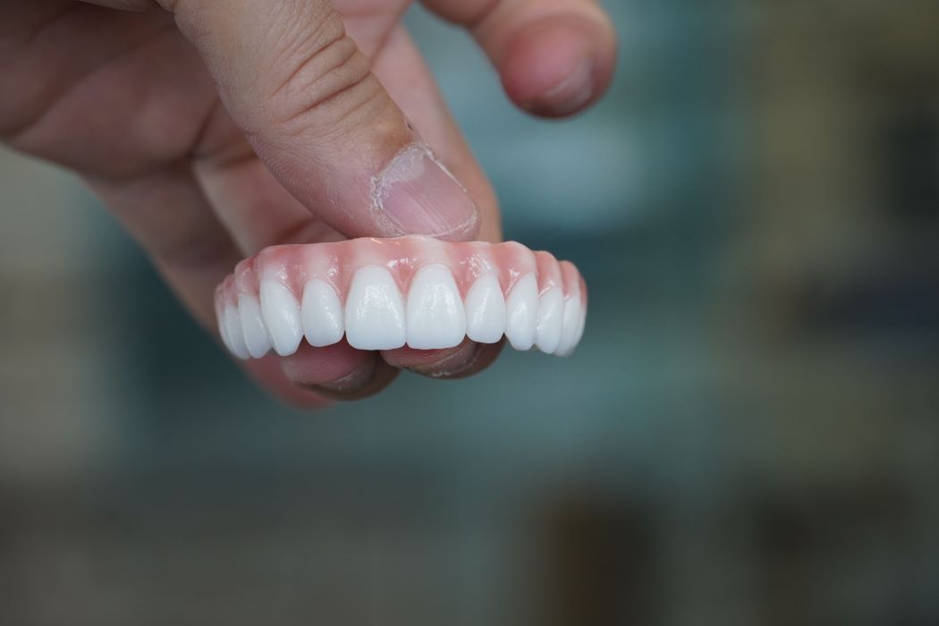 Fingers holding zirconia teeth that you can get in one day