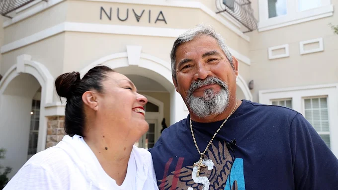 A man and his wife smiling outside of a Nuvia dental implant center
