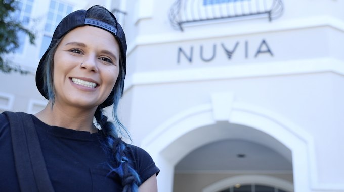 Woman smiling with her new teeth in front of the Nuvia office