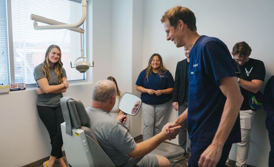 Dentist shaking a patient's hand as he looks in the mirror