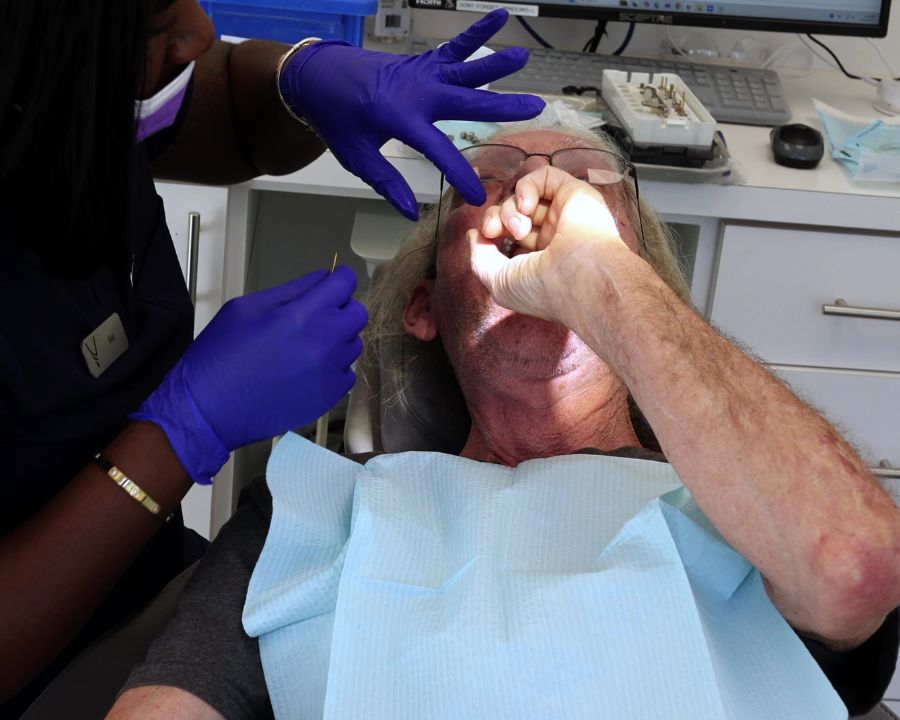 Man in dental chair being helped by assistant
