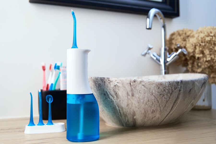 Waterpick for cleaning dental implants next to a sink and brushes